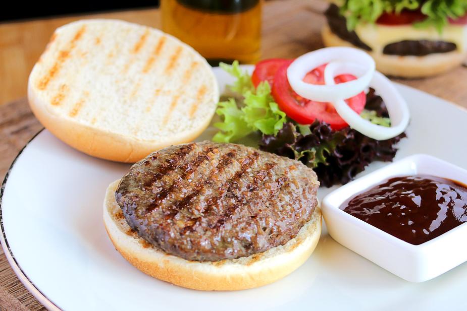 Delicious grilled burger with grass-fed ground beef on toasted bun, served with fresh toppings and sauce